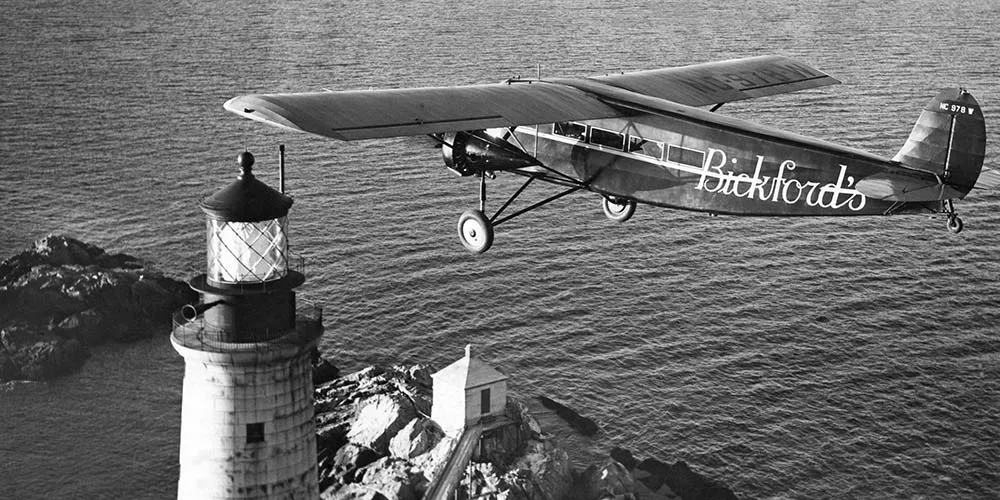Trimotor airplane flys over Graves Light in Maine in 1947