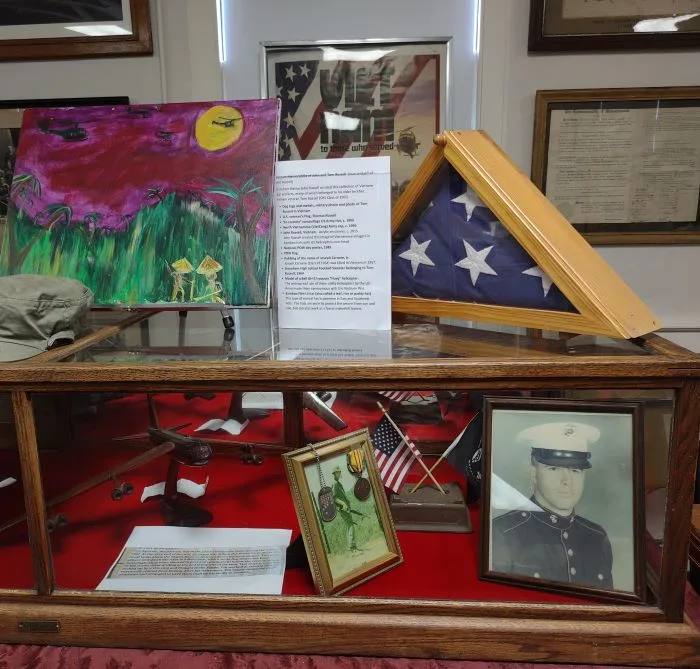Image of artifacts in a musuem display case including US flag and image of a Marine private.
